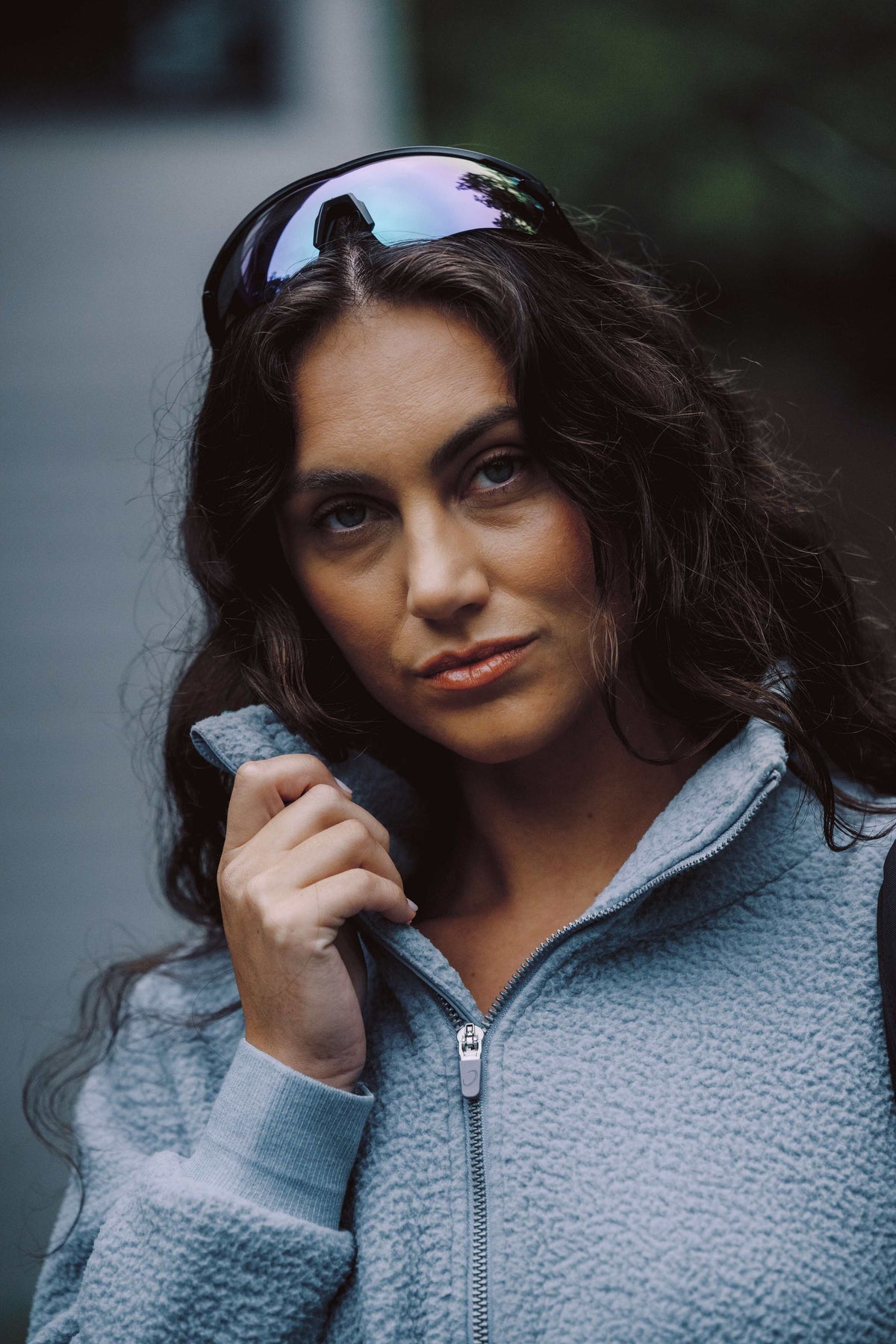 Woman in a teal sherpa vest by a stone fireplace