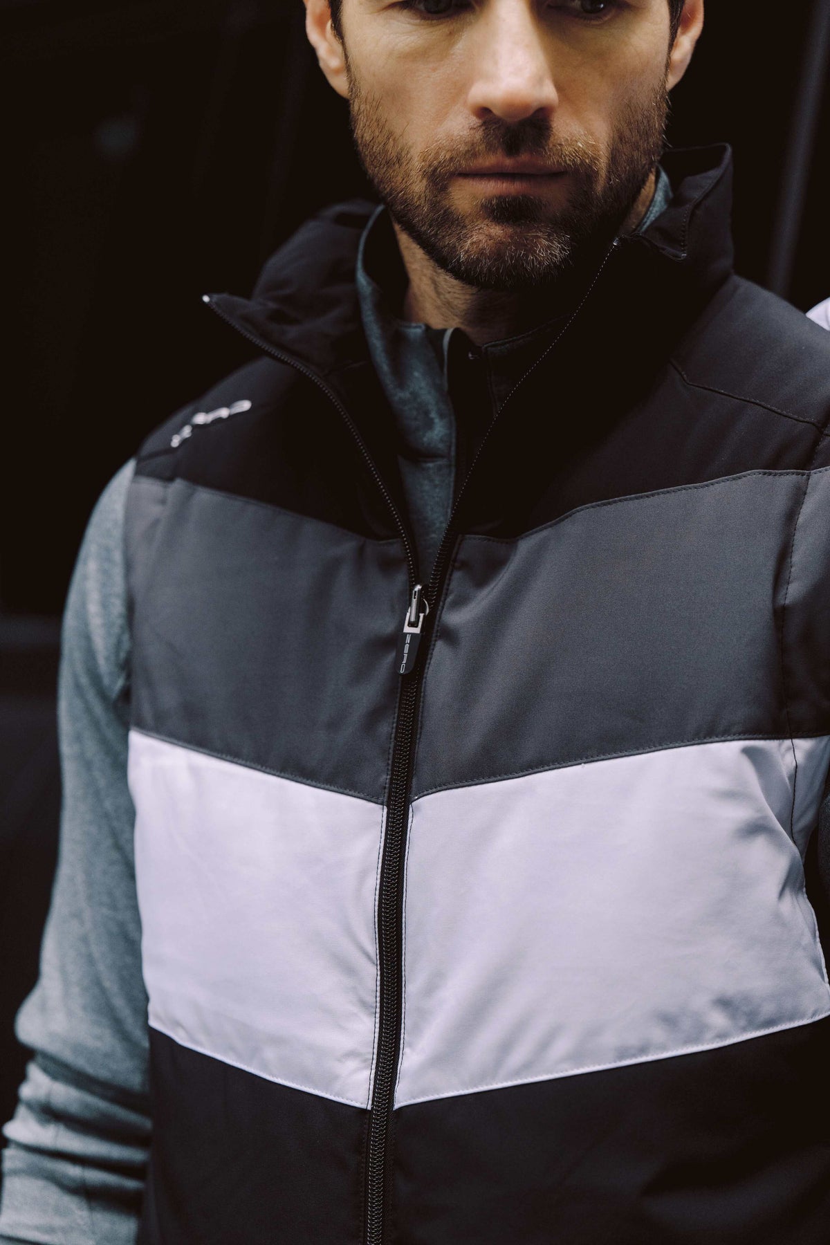 Man leaning on a wall in a dark green quarter-zip