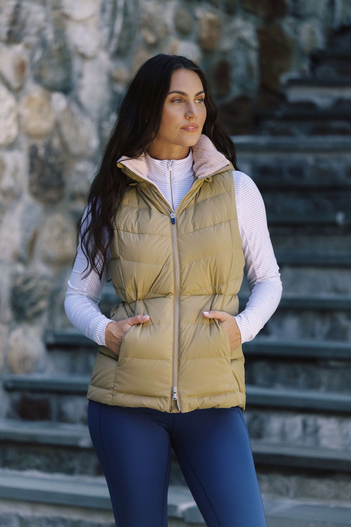 Woman in an olive puffer vest on stone steps